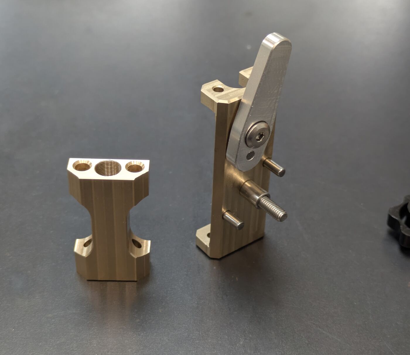 Two upright brass-coloured machined components on a work surface